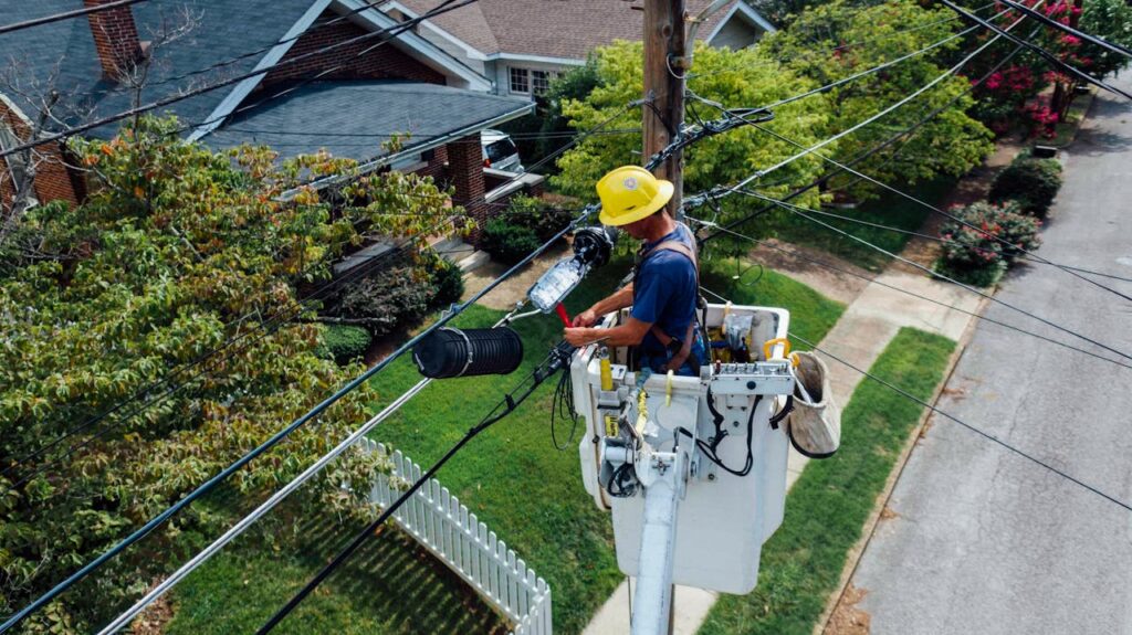 Quizzes Electrician in a bucket lift repairing power lines from a utility pole in a suburban neighborhood.