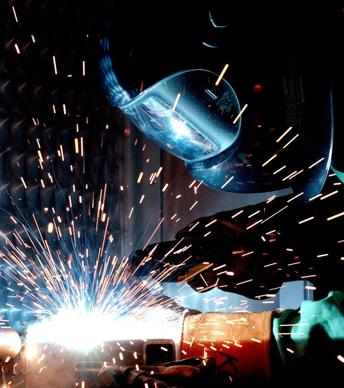 Surveys A focused welder works with metal in an industrial setting, creating vibrant sparks.